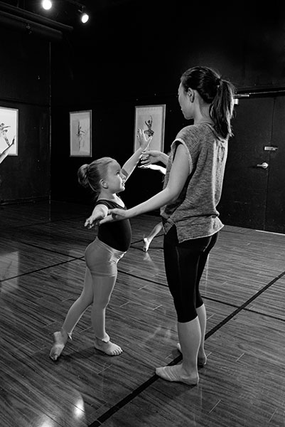 Dance Teacher helping young girl student with positioning at Fredericksburg Studio of the Arts