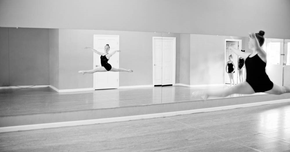 dance student midair reviewing herself in the mirror